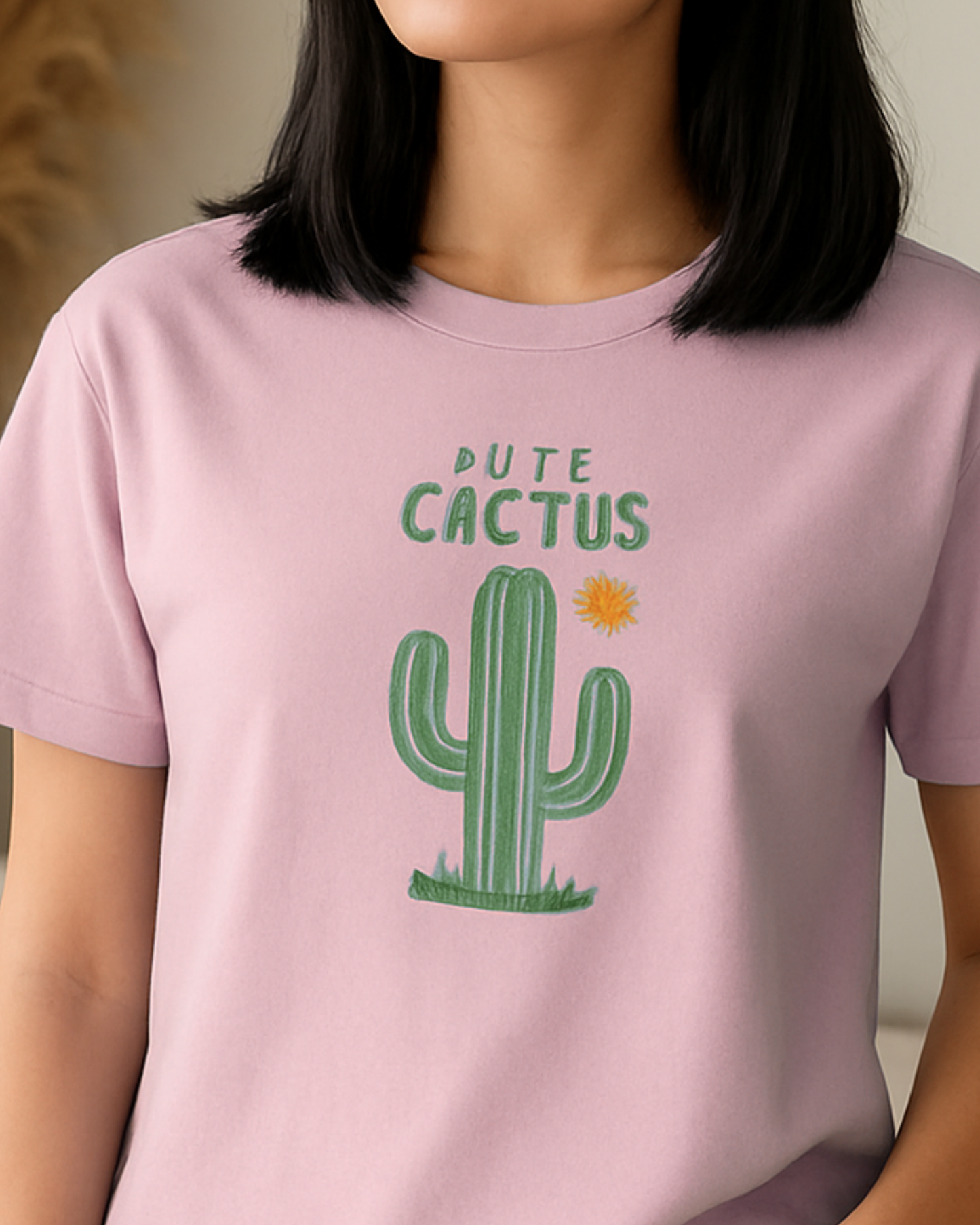 Person wearing a pink t-shirt with a cactus graphic and text.