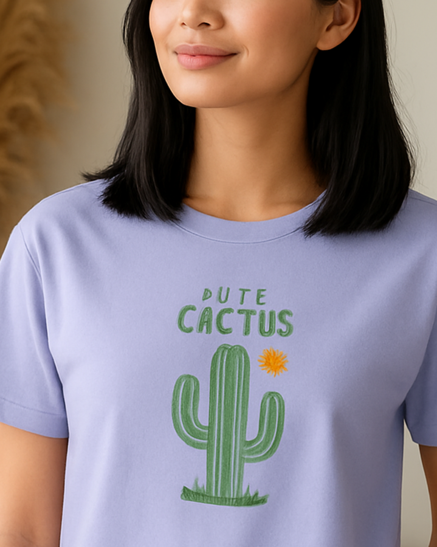 Person wearing a lavender t-shirt with a cactus graphic and text.