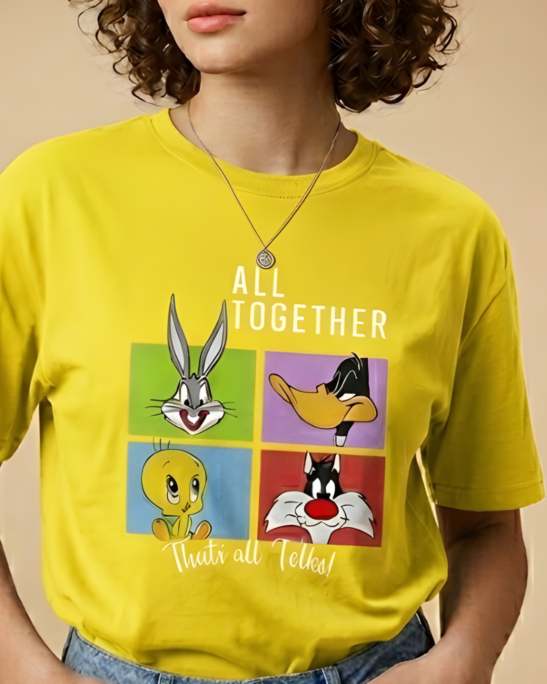 Person wearing a yellow t-shirt with Looney Tunes characters and text.