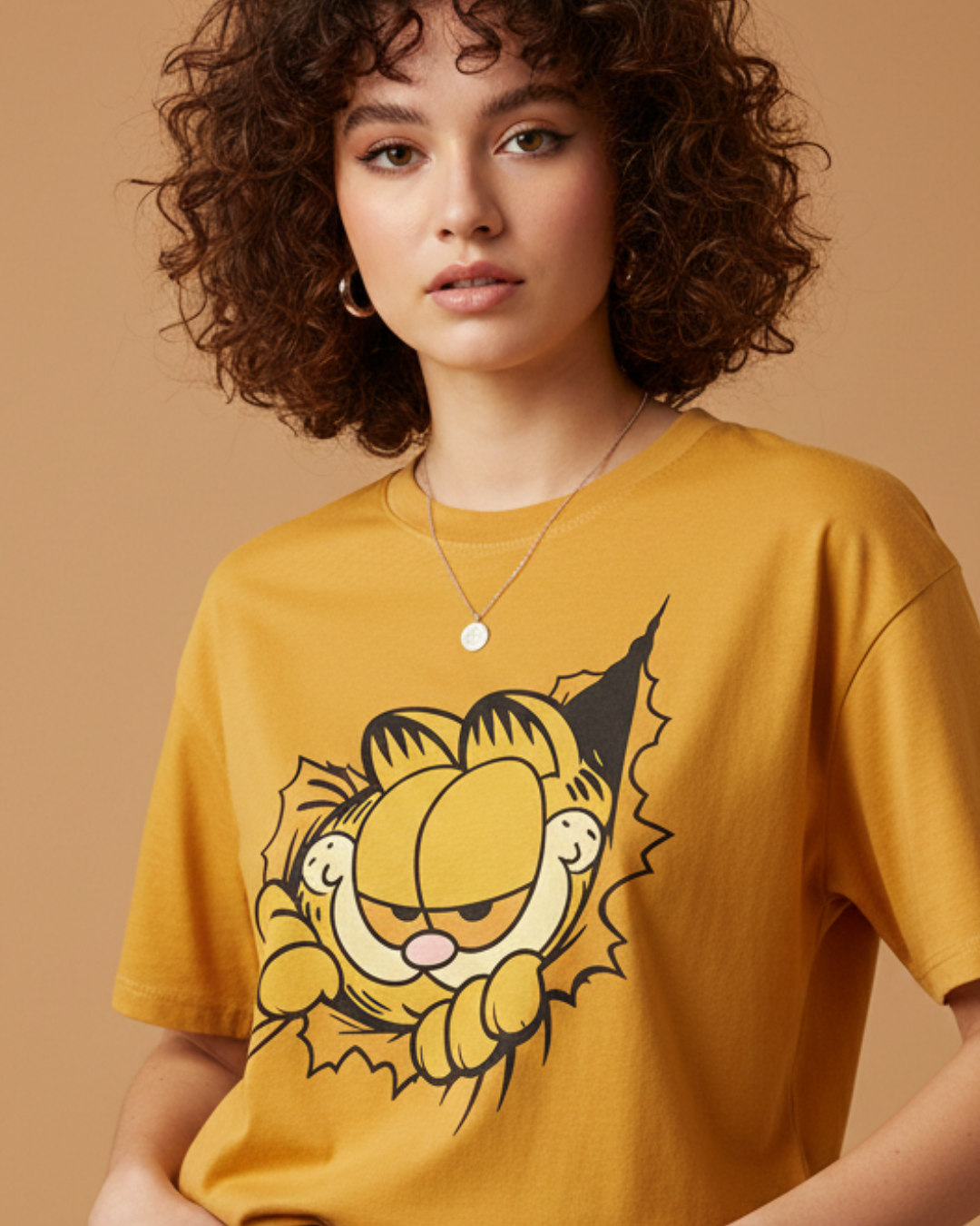 Person wearing a mustard yellow t-shirt with a cartoon character on a beige background