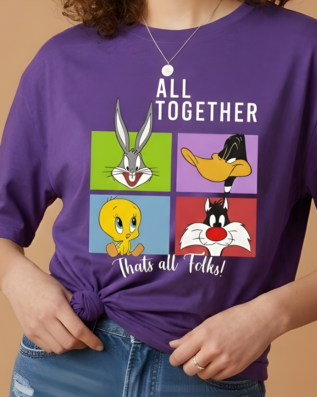 Person wearing a purple t-shirt with Looney Tunes characters and text on a beige background