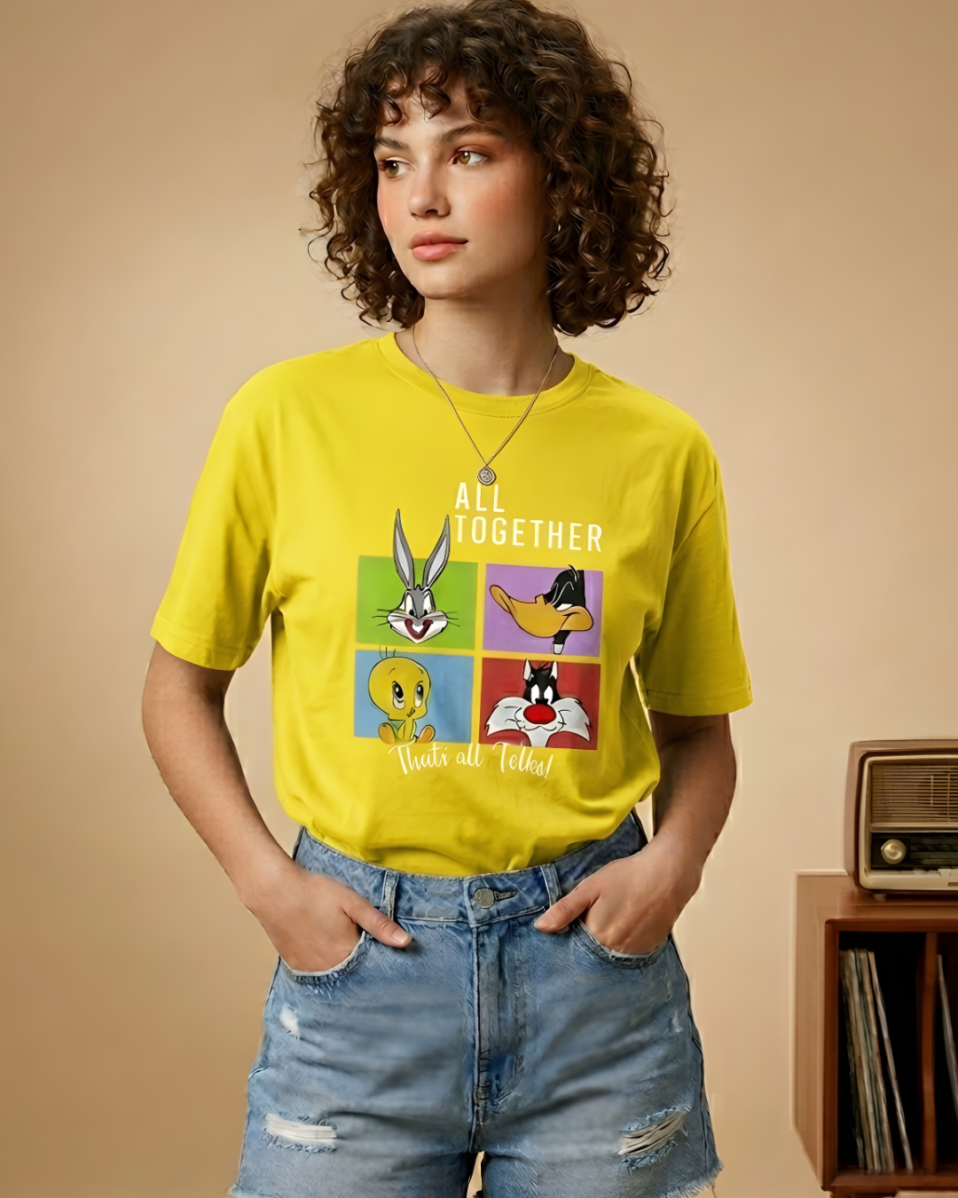 Person wearing a yellow t-shirt with Looney Tunes characters and text, standing against a beige background.