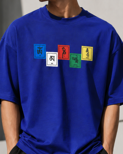 A close-up of a person wearing a royal blue t-shirt with five colorful square panels across the chest displaying Tibetan script.