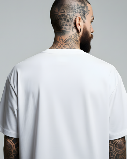 Man wearing a white t-shirt with visible tattoos on his arms and back against a gray background