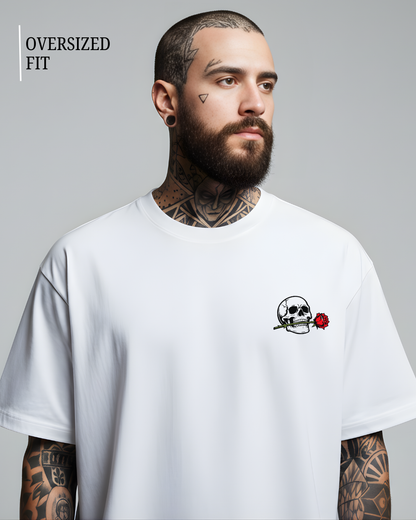 Man wearing a white oversized t-shirt with a skull and rose design on a gray background