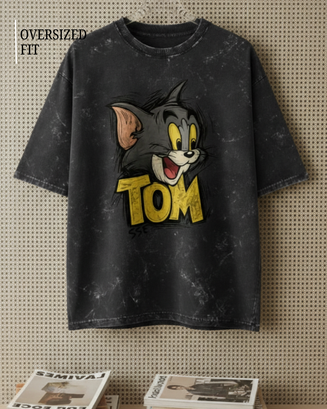 Black t-shirt with cartoon character and 'Tom' text on a textured wall background