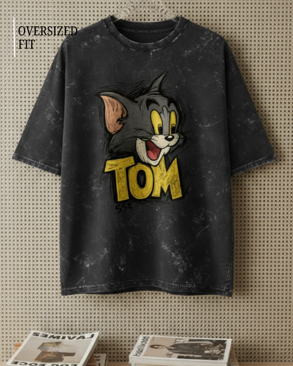 Black t-shirt with cartoon character and 'Tom' text on a textured wall background