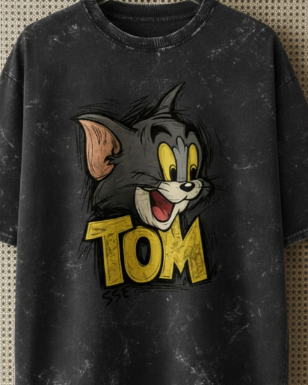 Black t-shirt with cartoon character and 'Tom' text on a textured background