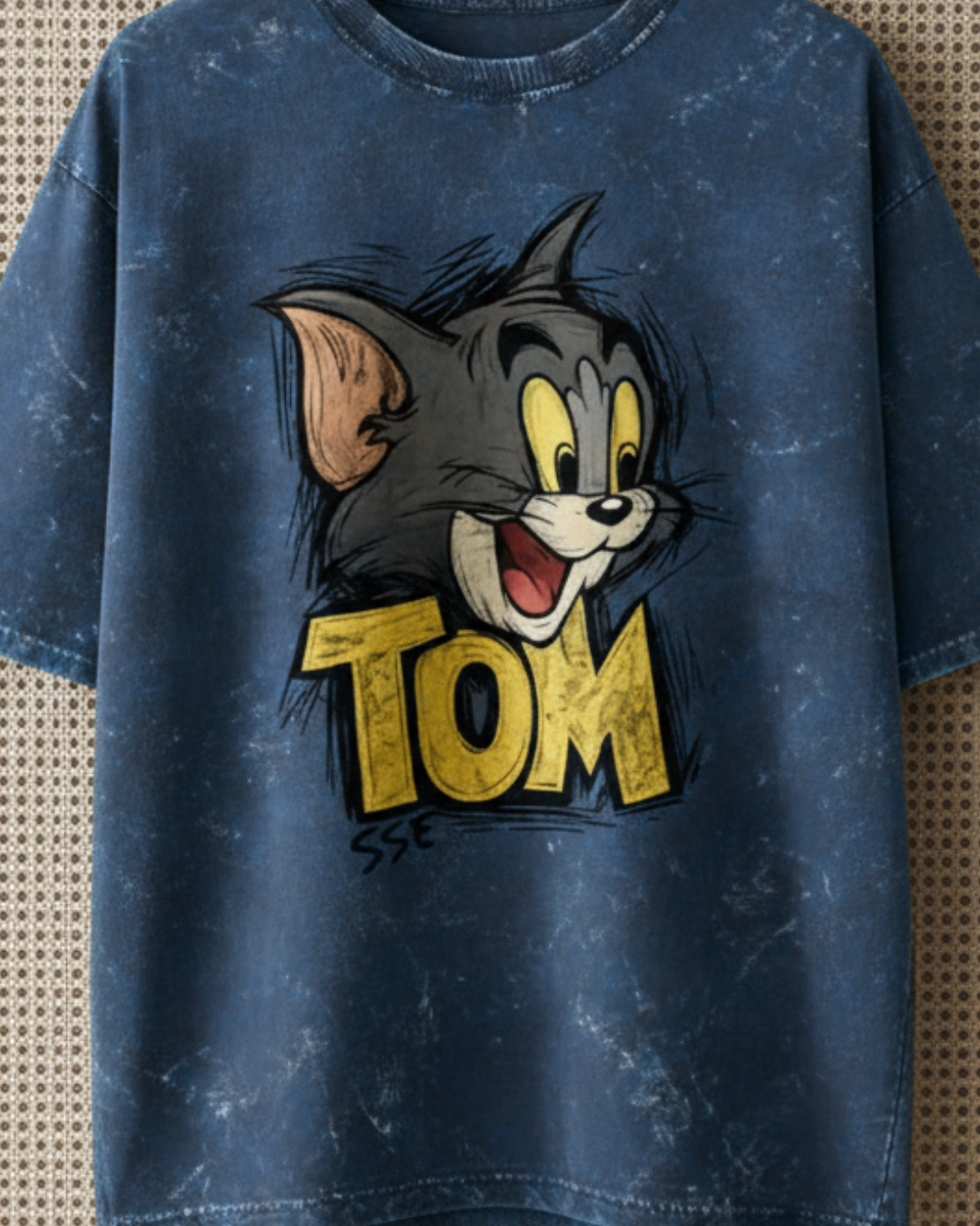 Blue t-shirt with a cartoon character and 'Tom' text on a textured background