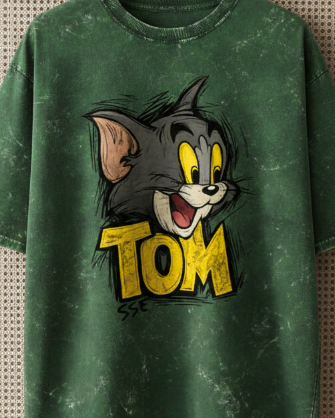 Green t-shirt with a cartoon character and 'Tom' text on a textured background