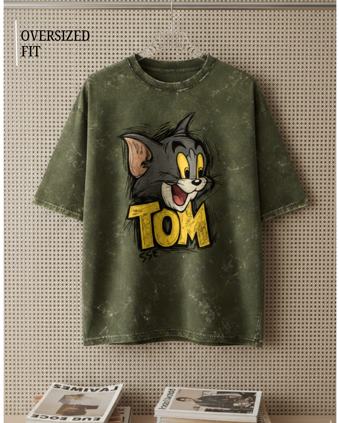 Olive Green t-shirt with cartoon character and 'Tom' text on a textured wall background
