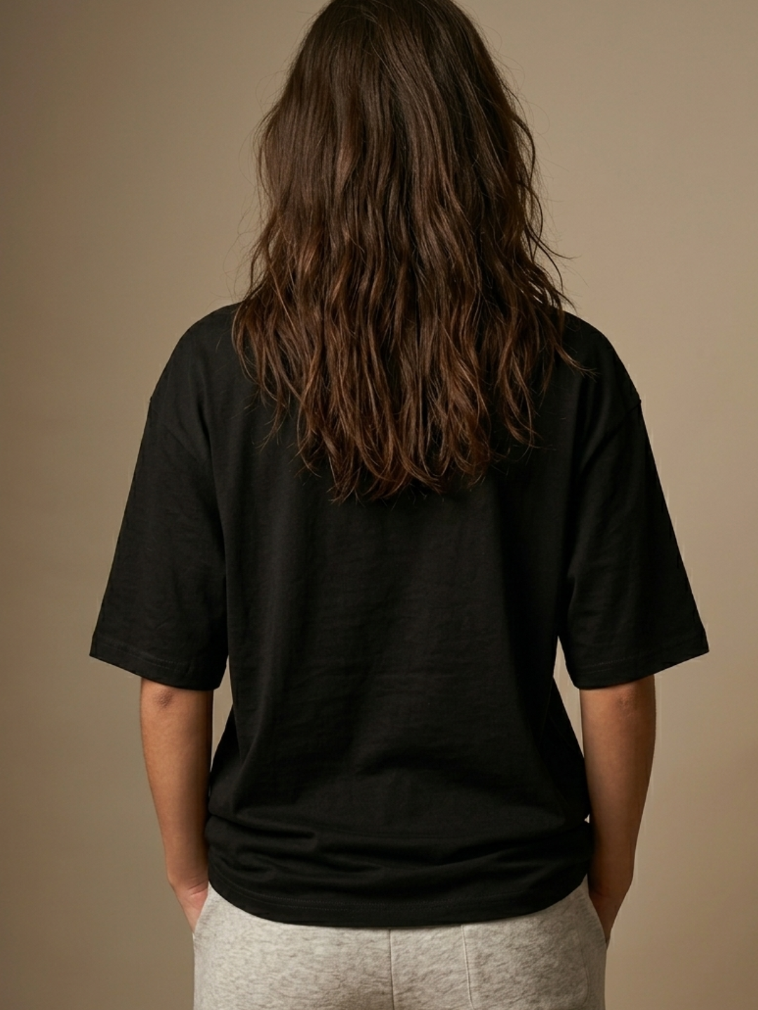 Person wearing a black t-shirt against a brown background
