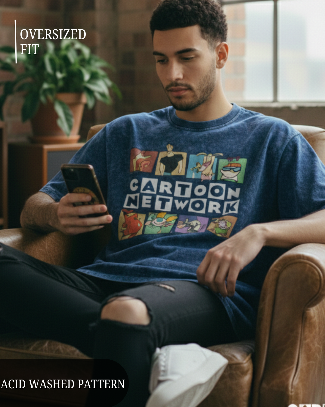 Man wearing a blue Cartoon Network t-shirt sitting on a brown leather chair.