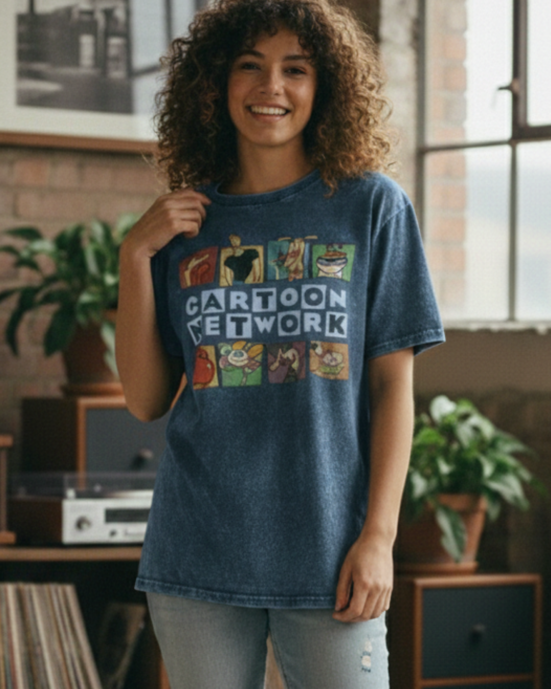 Woman wearing a blue 'Cartoon Network' t-shirt in a room with plants and vintage equipment.