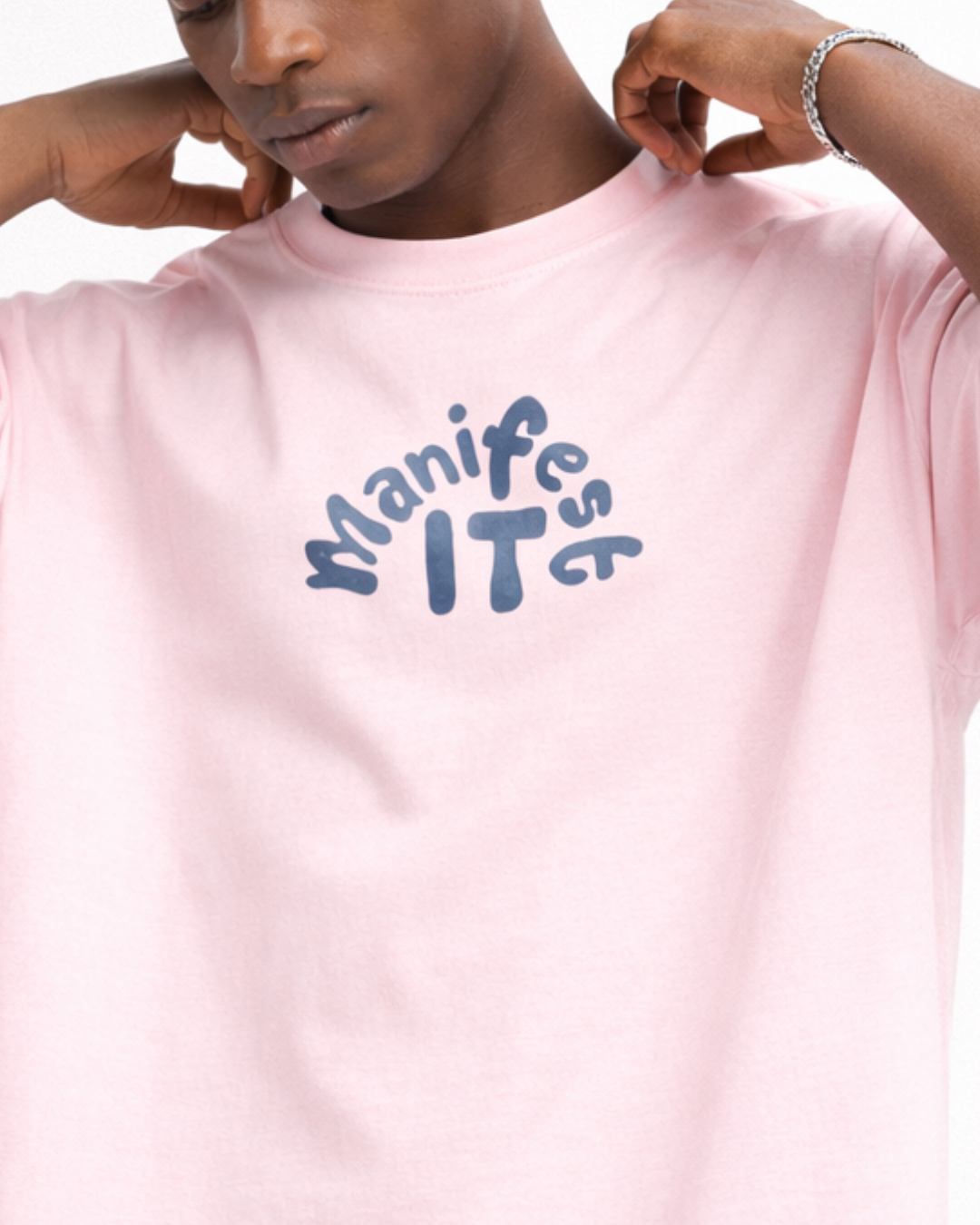 Person wearing a pink t-shirt with 'Manife ITs' text in blue.